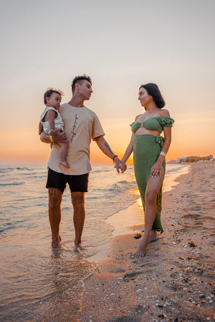 A warm, cinematic shot of a family playing barefoot on soft sand under golden afternoon light.
