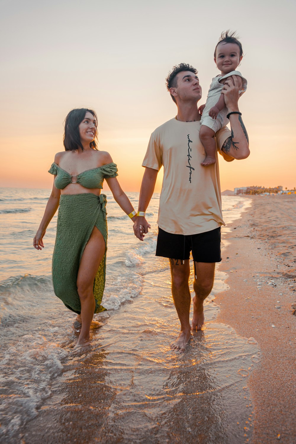 um homem e uma mulher que seguram um bebê na praia