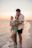 a man and woman holding a baby on the beach