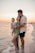 a man and woman holding a baby on the beach