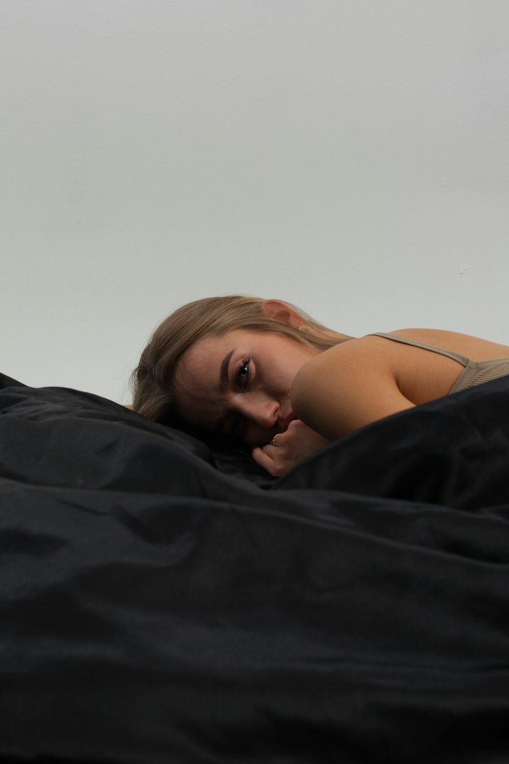 a woman laying in bed with a black comforter