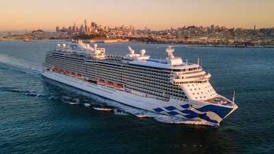 a large cruise ship in the ocean with a city in the background