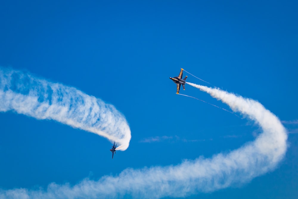 a couple of airplanes flying through a blue sky