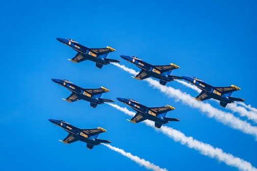 a group of fighter jets flying through a blue sky