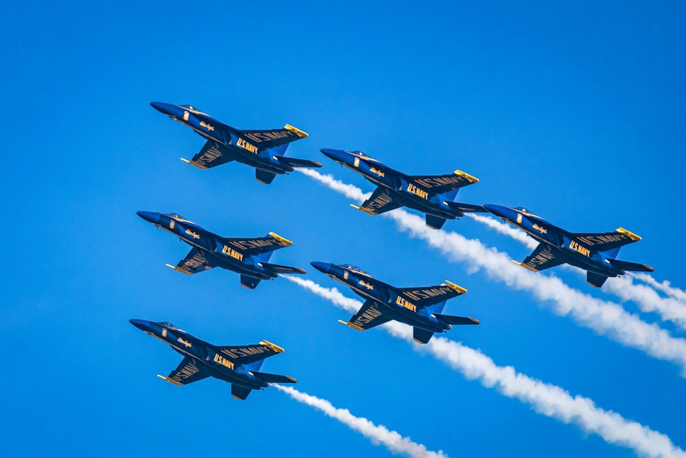 a group of fighter jets flying through a blue sky