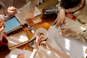 A group of diverse writers sharing ideas around a wooden table in a sunlit room.