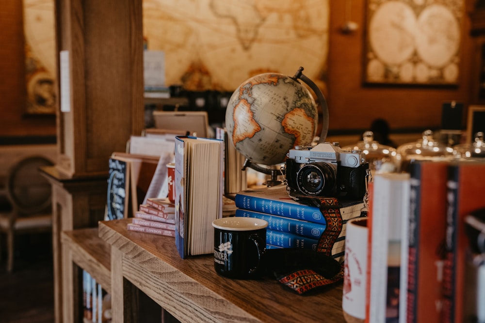 a wooden table topped with books and a globe