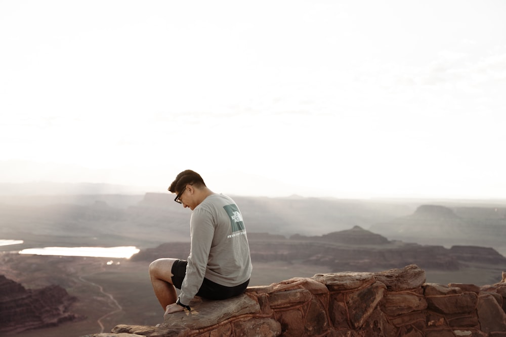 a man sitting on top of a rock wall