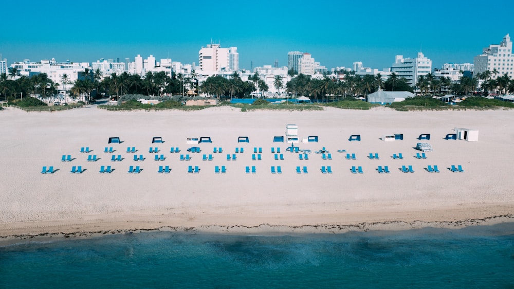 eine Luftaufnahme eines Strandes mit Stühlen und Gebäuden im Hintergrund