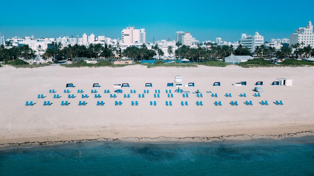 an aerial view of a beach with chairs and buildings in the background