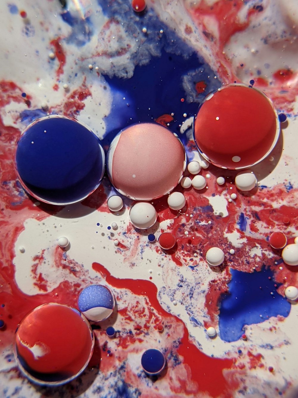 a close up of a bowl of paint with red, white, and blue colors
