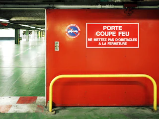 a red box with a sign on it in a parking garage