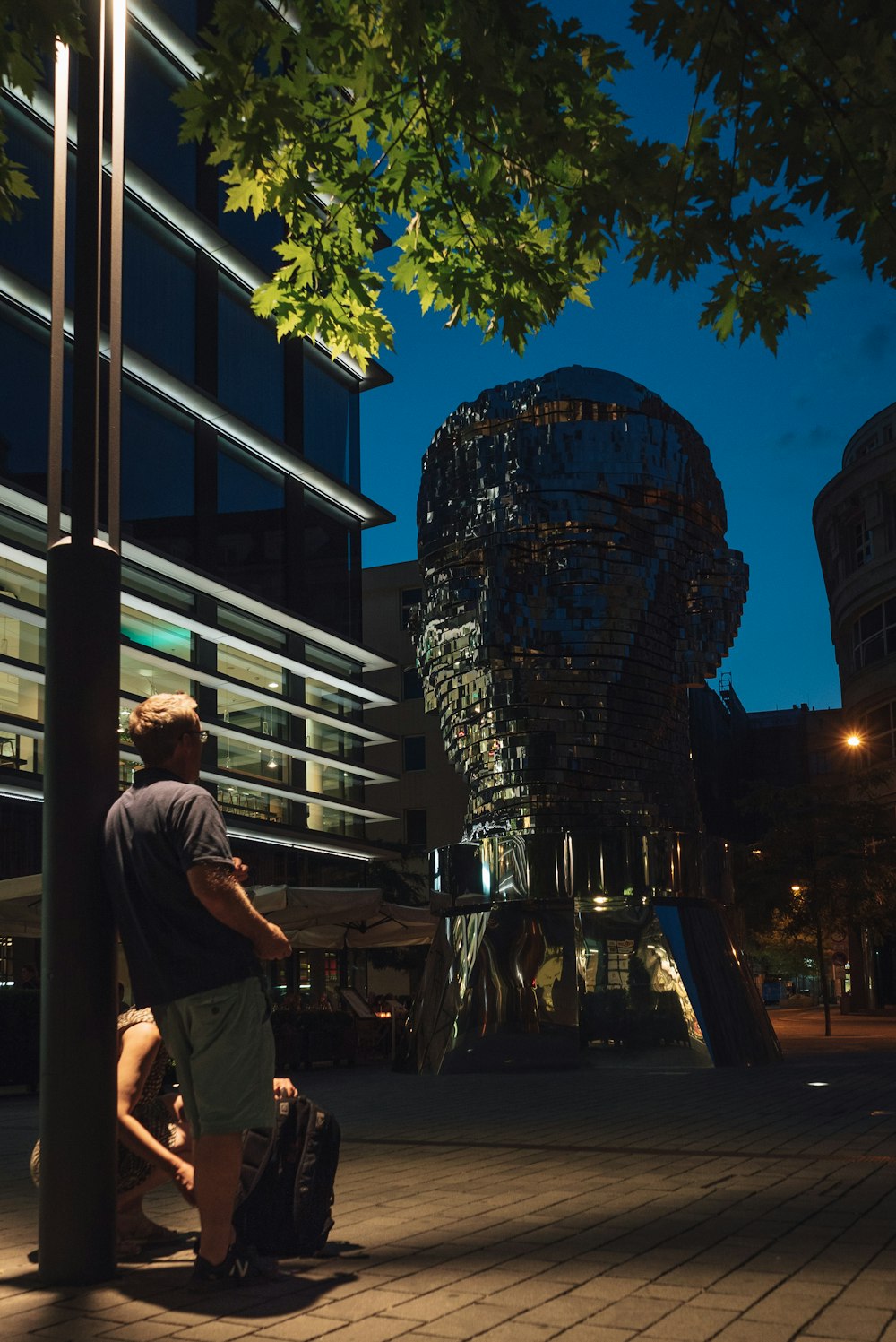 a man leaning against a pole next to a tall building