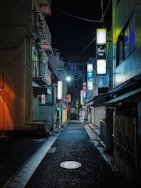 A still from a dark, atmospheric short film showing a dimly lit alley with flickering neon signs.