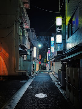 A still from a dark, atmospheric short film showing a dimly lit alley with flickering neon signs.
