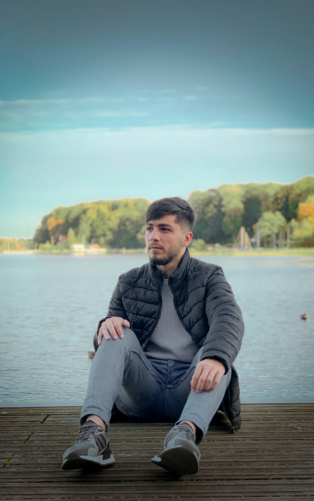 a man sitting on a dock next to a body of water