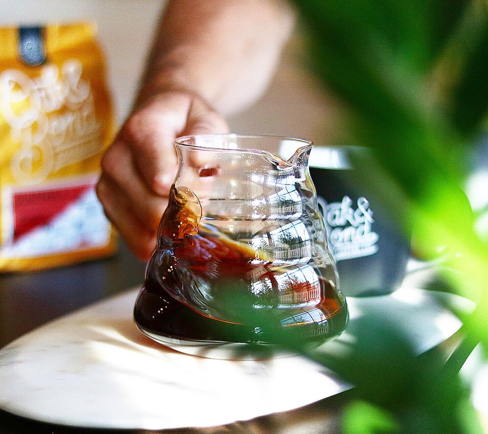 a person pouring liquid into a glass vase