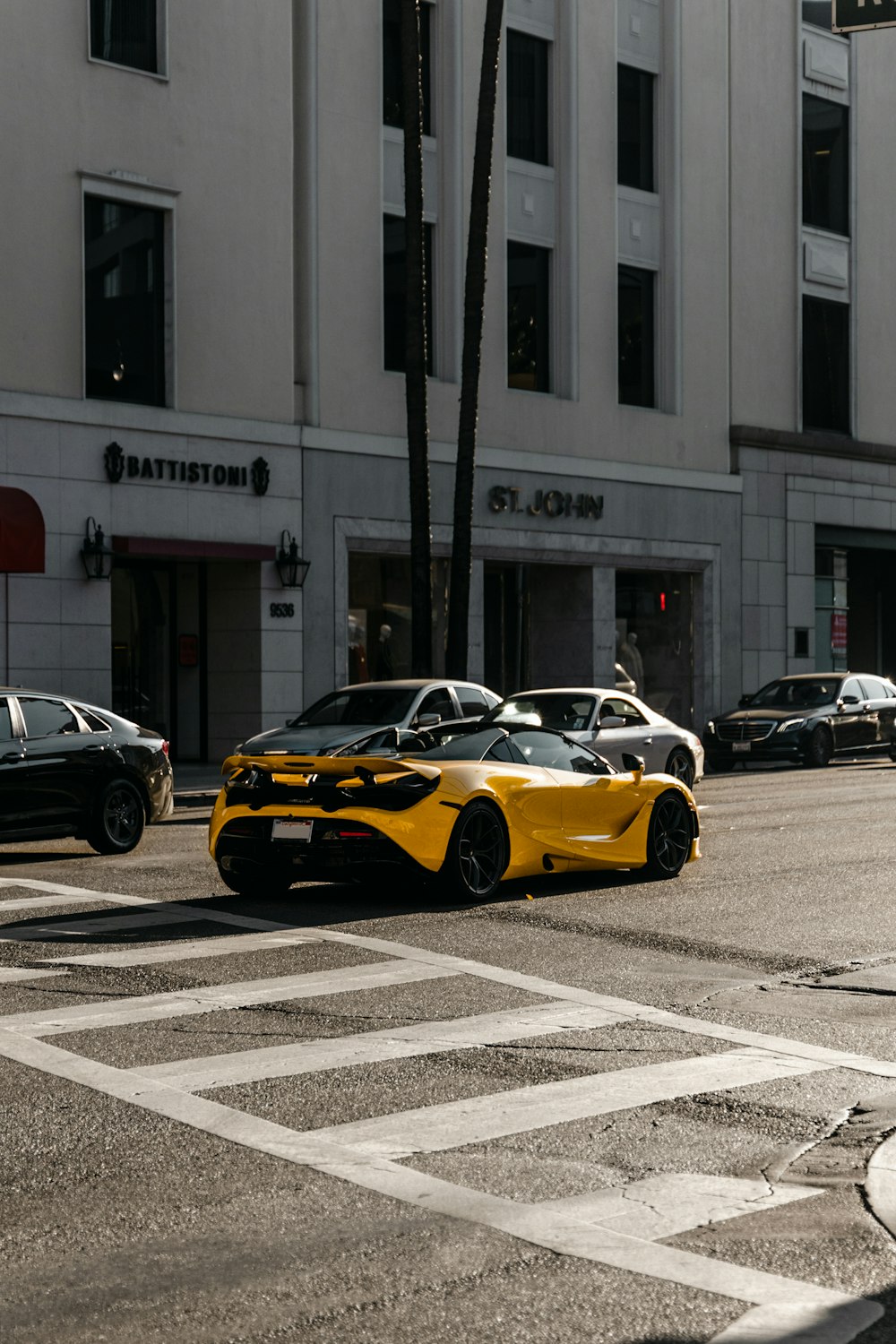 a yellow sports car driving down a city street