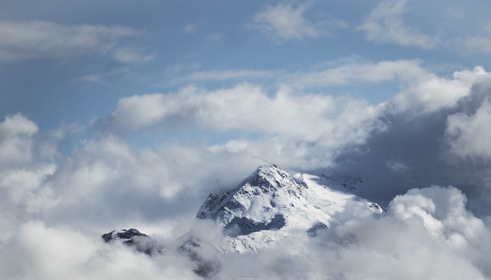 a snow covered mountain surrounded by clouds