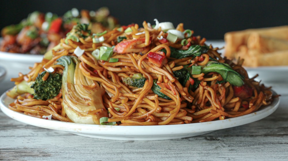 a plate of noodles with broccoli and other vegetables