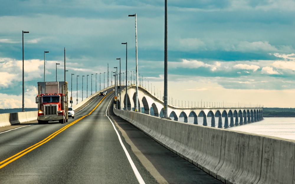 a semi truck driving across a bridge over water