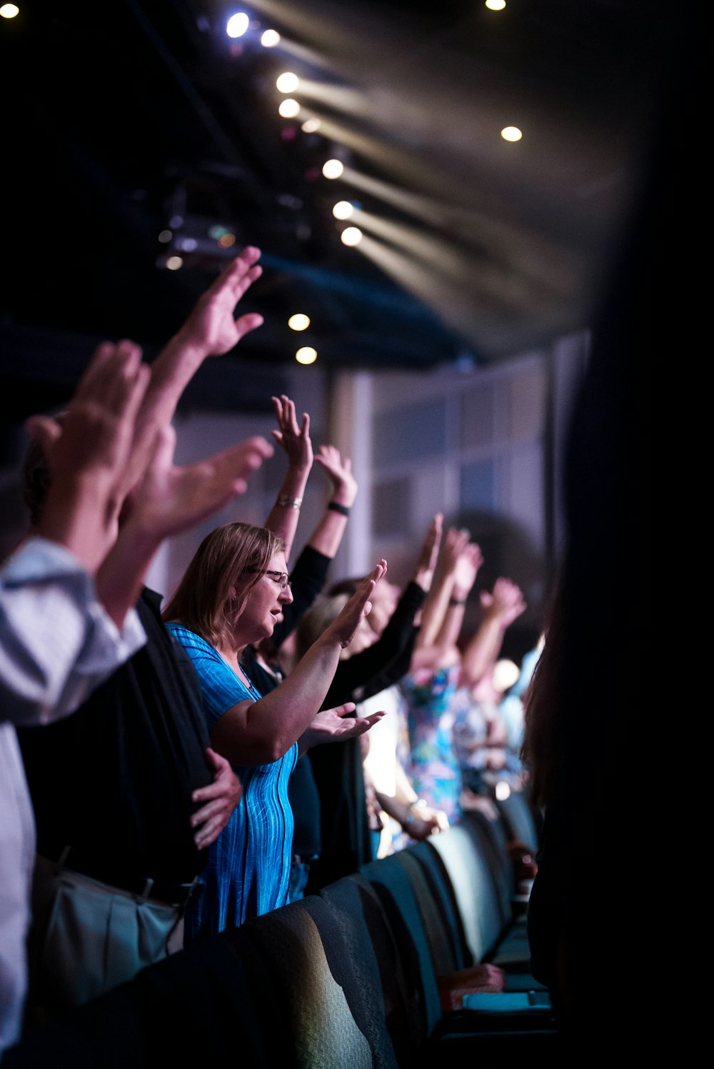 a group of people sitting in a room with their hands in the air