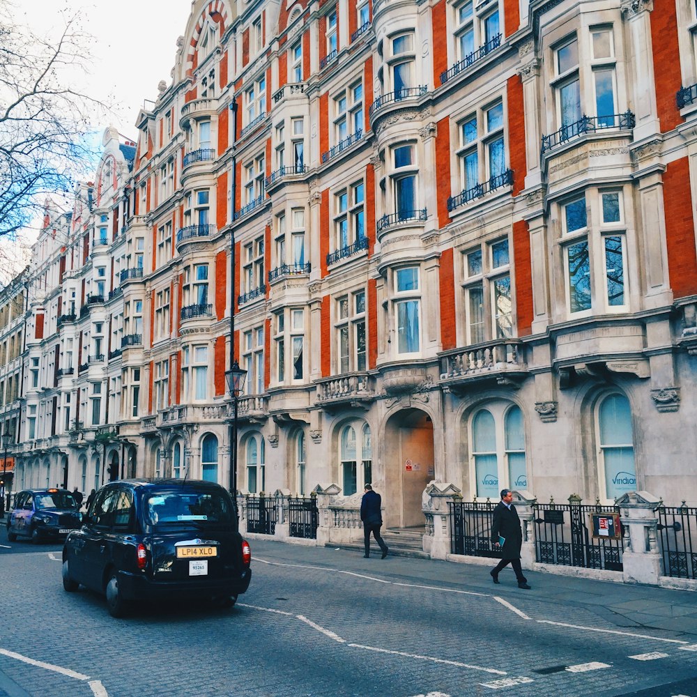 a black car driving down a street next to tall buildings