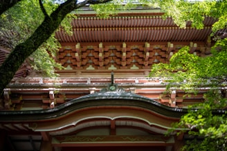 A skilled craftsman carefully working on wooden beams in a traditional Japanese construction site surrounded by lush greenery.