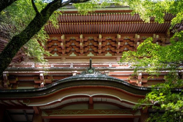 A skilled craftsman carefully working on wooden beams in a traditional Japanese construction site surrounded by lush greenery.
