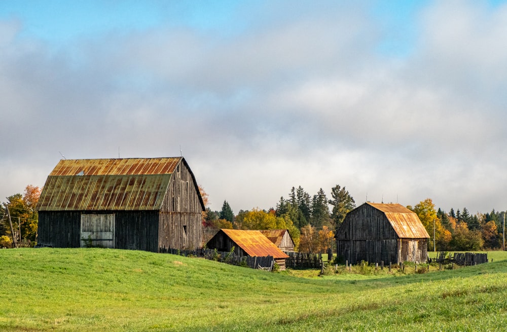an old barn sits on a grassy hill