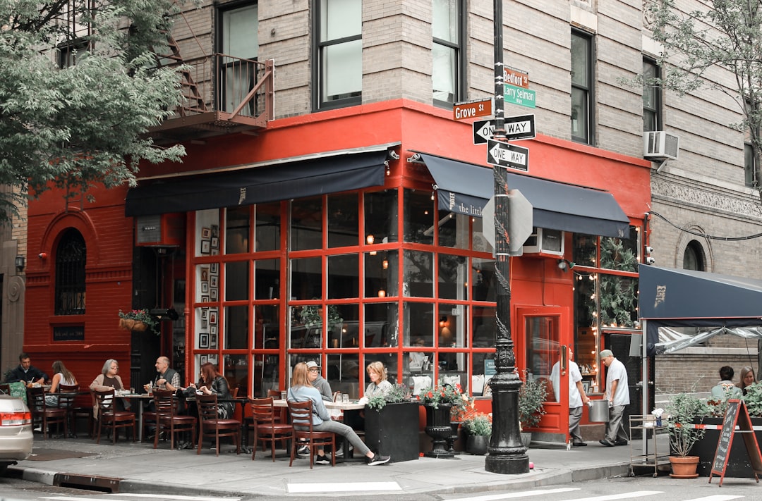 a group of people sitting at tables outside of a restaurant,