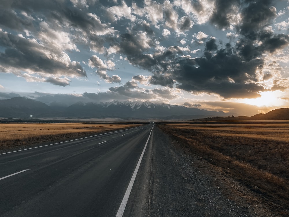 a long road with a cloudy sky in the background