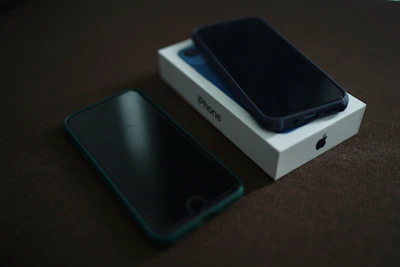 A close-up shot of a person comparing two smartphone boxes on a wooden table.