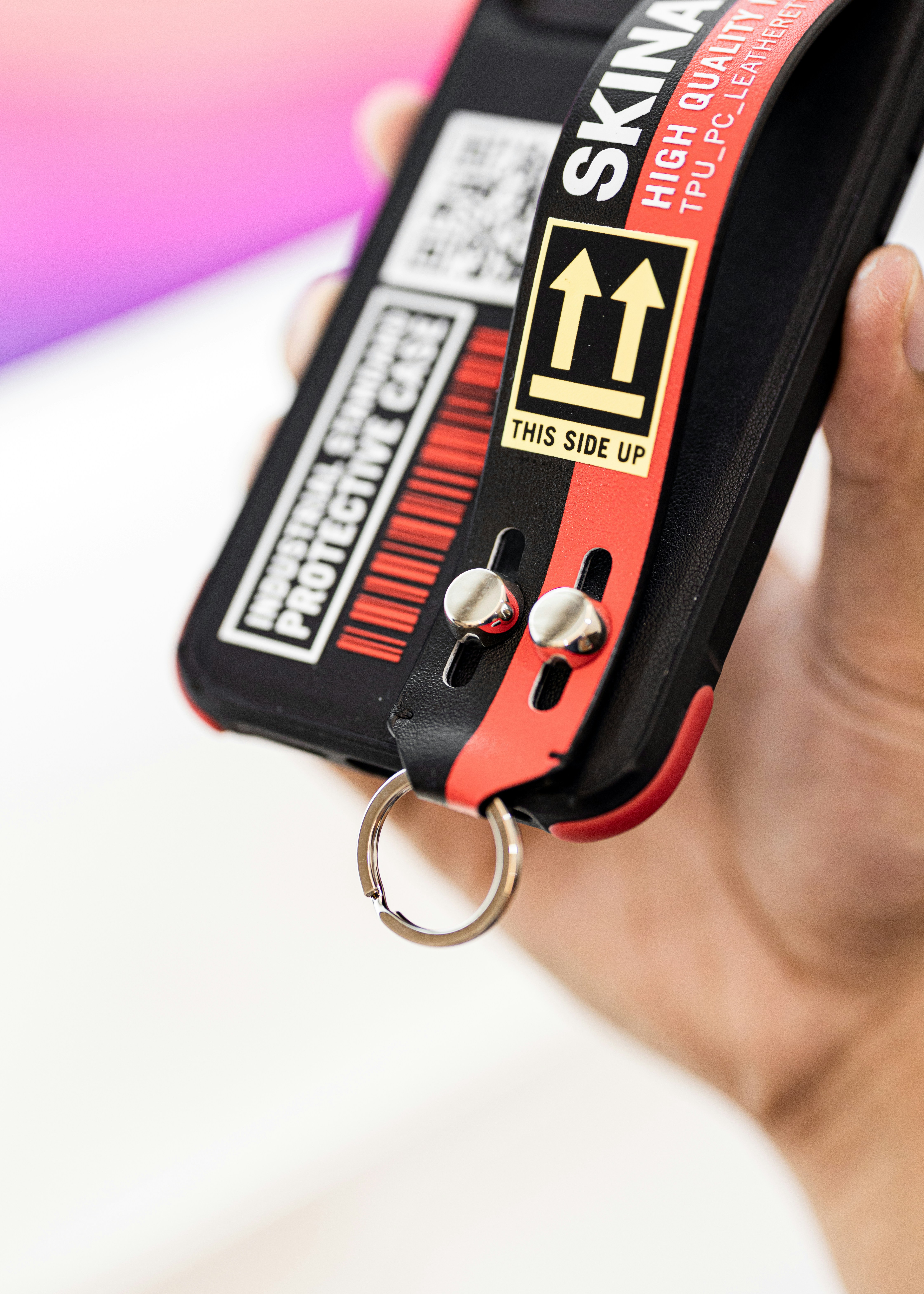 a hand holding a cell phone with a keychain attached to it