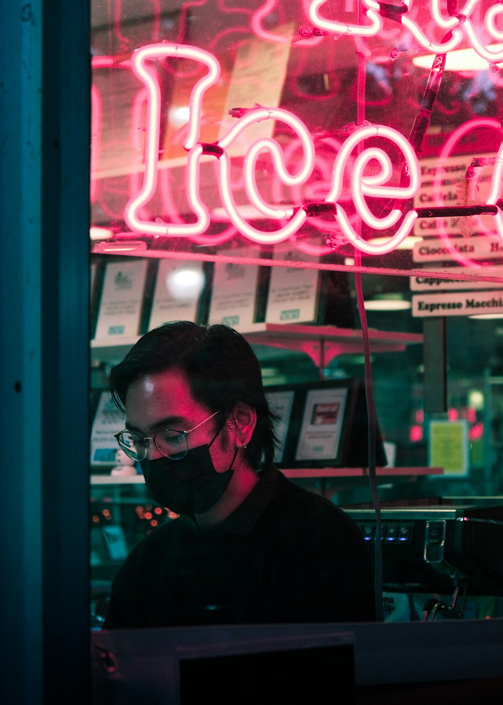 a man wearing a face mask in front of a neon sign