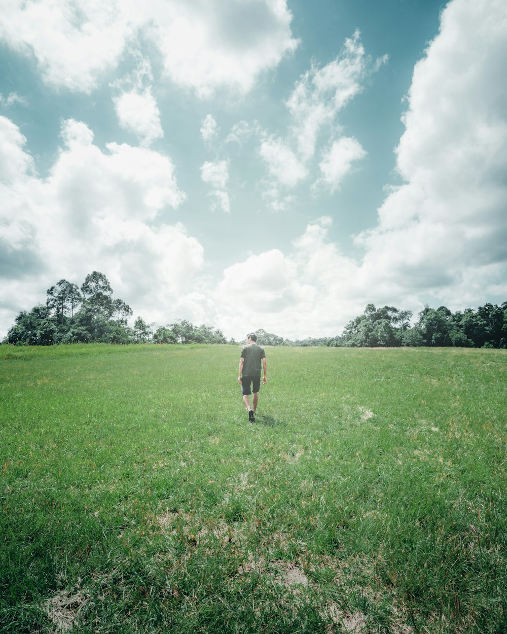 a man walking across a lush green field