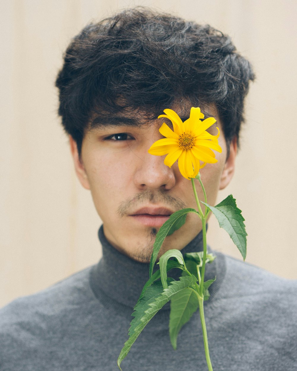a man holding a flower in front of his face