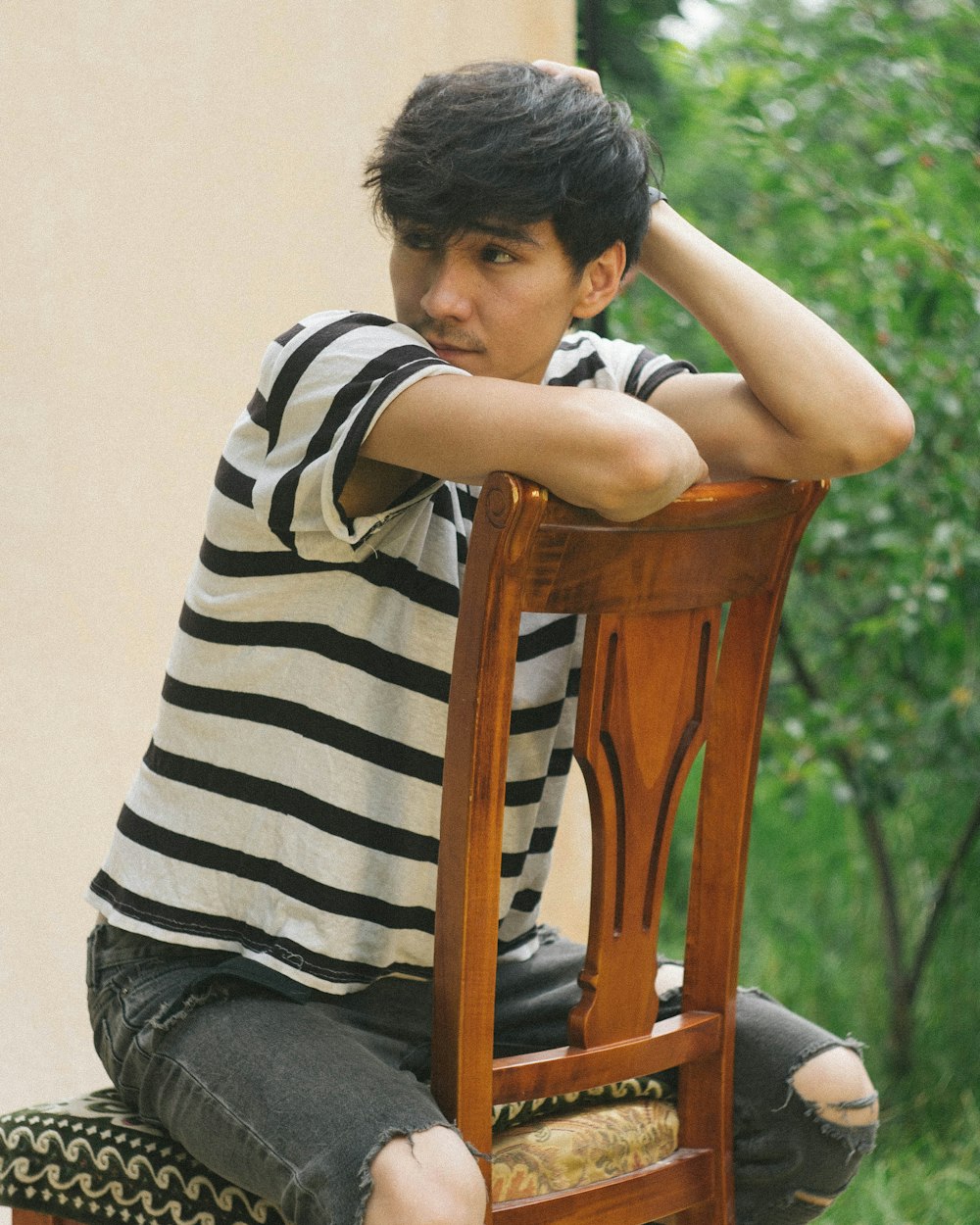 a young man sitting on top of a wooden chair