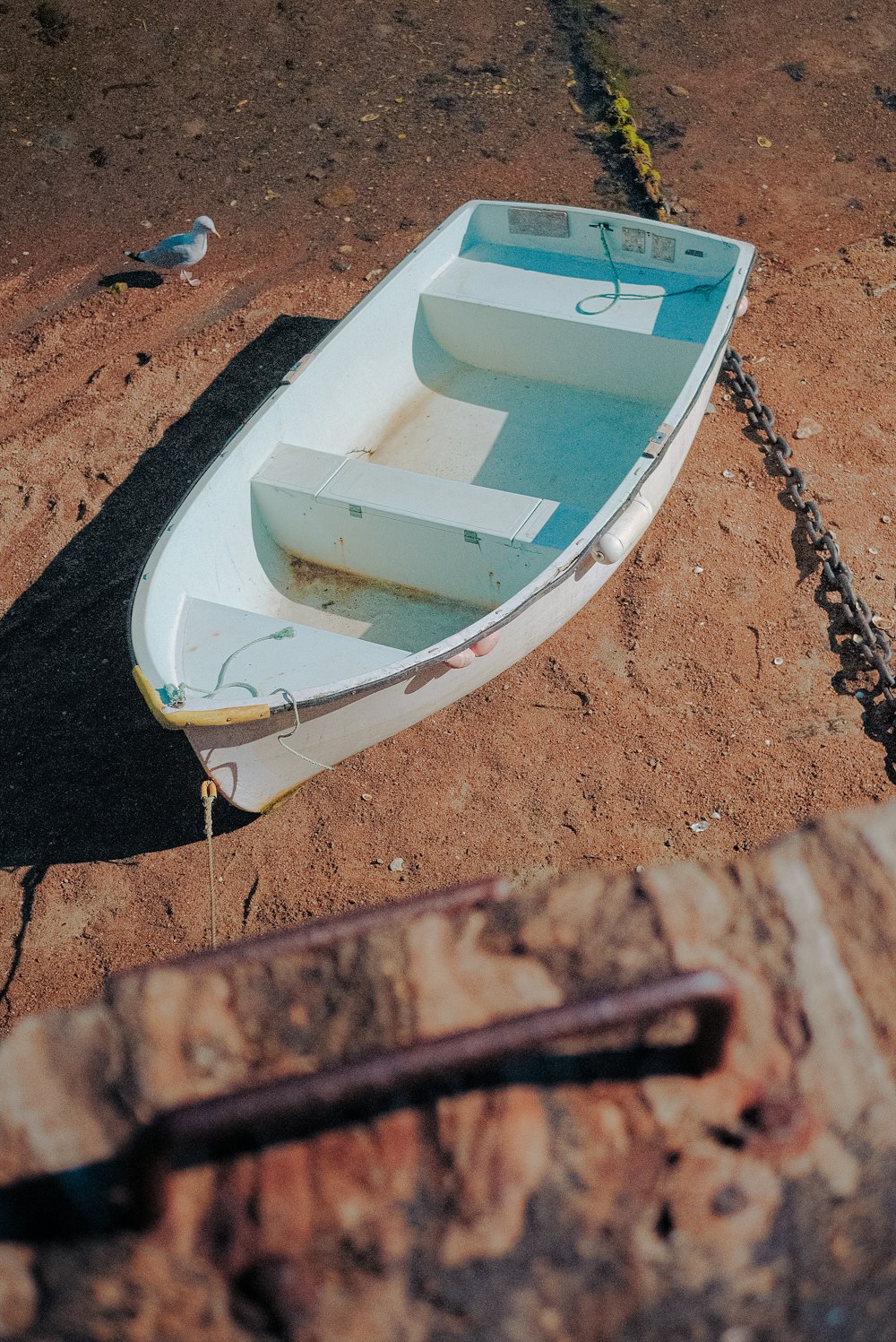 a small white boat sitting on top of a sandy beach