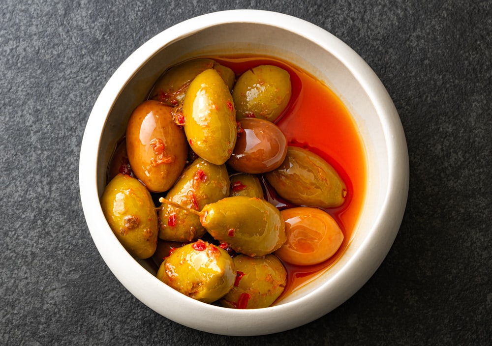 eine weiße Schüssel gefüllt mit Oliven und Tomaten