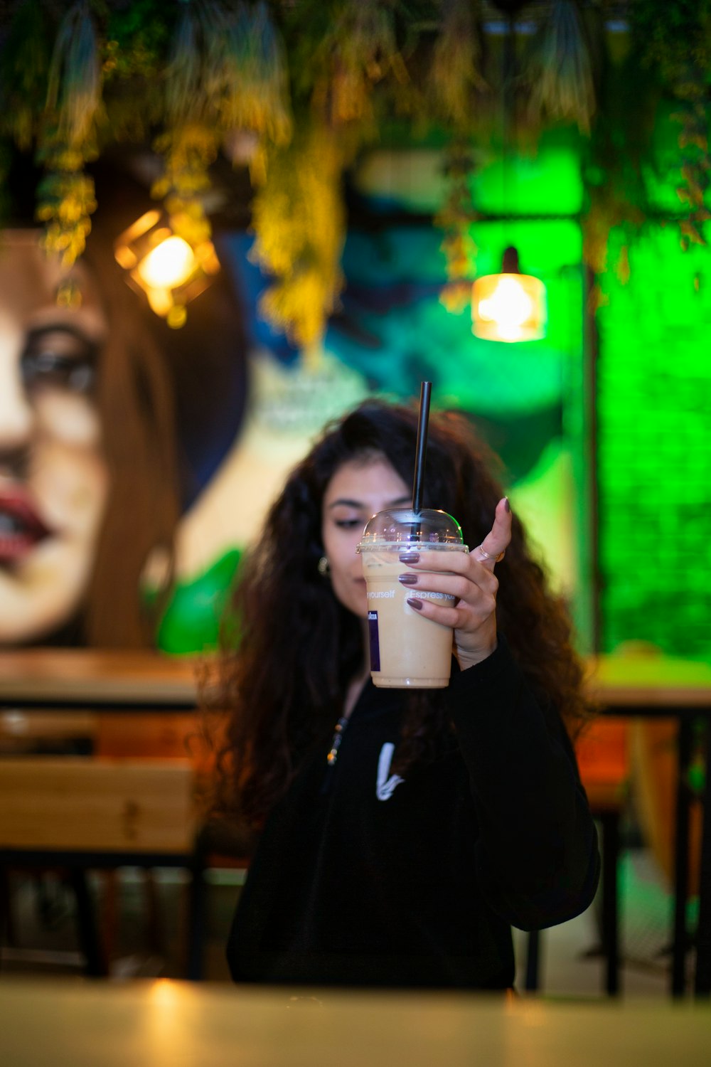 Una mujer sosteniendo una bebida frente a su cara