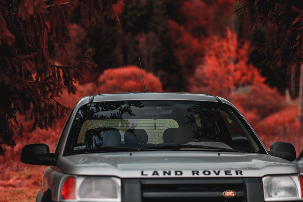 a silver land rover is parked in front of some trees