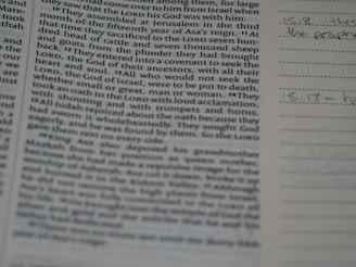 A close-up of a book or bible page showing printed text on the left side. The text is about a religious or historical topic, mentioning leaders and events. Handwritten notes can be seen on the lined section to the right, indicating engagement with the text.