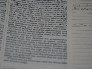 A close-up of a book or bible page showing printed text on the left side. The text is about a religious or historical topic, mentioning leaders and events. Handwritten notes can be seen on the lined section to the right, indicating engagement with the text.