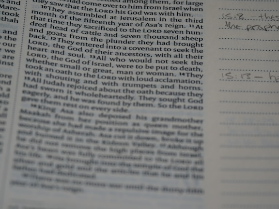 A close-up of a book or bible page showing printed text on the left side. The text is about a religious or historical topic, mentioning leaders and events. Handwritten notes can be seen on the lined section to the right, indicating engagement with the text.