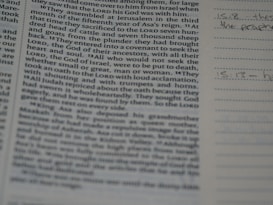 A close-up of a book or bible page showing printed text on the left side. The text is about a religious or historical topic, mentioning leaders and events. Handwritten notes can be seen on the lined section to the right, indicating engagement with the text.