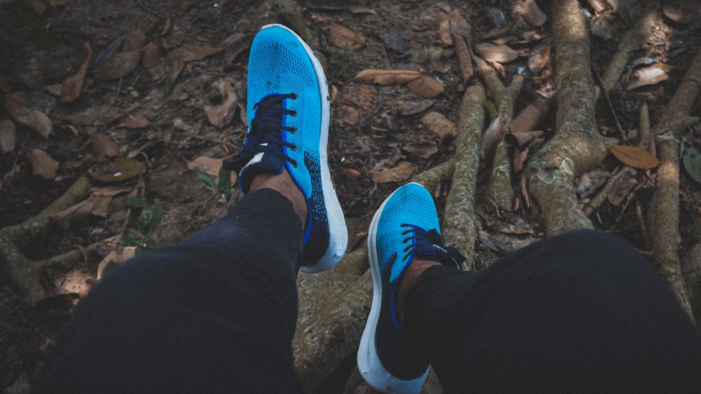 a person wearing blue shoes standing in the woods