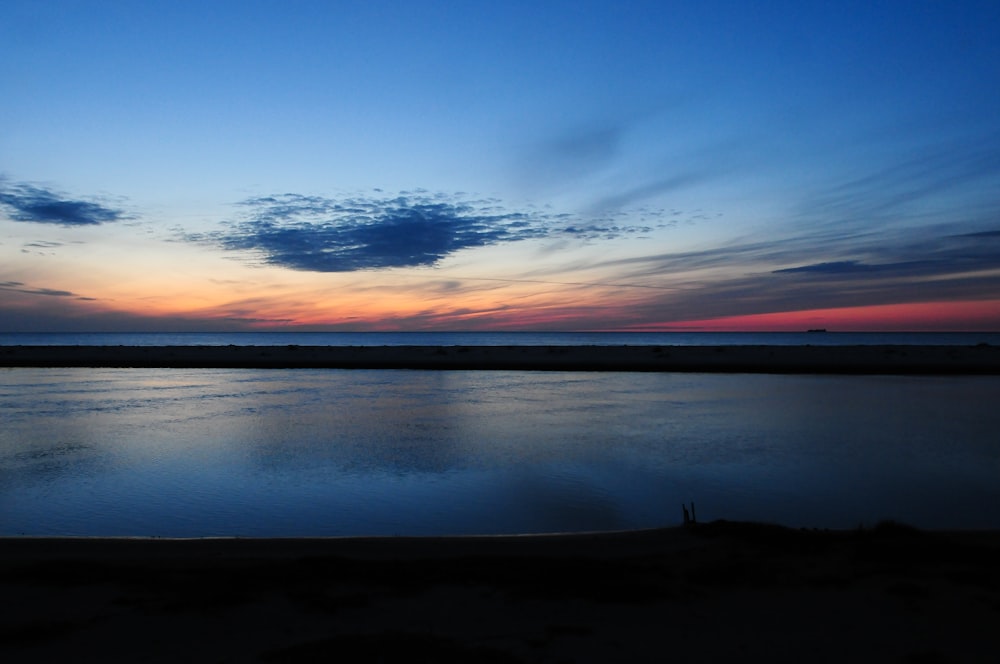 a body of water with a sunset in the background