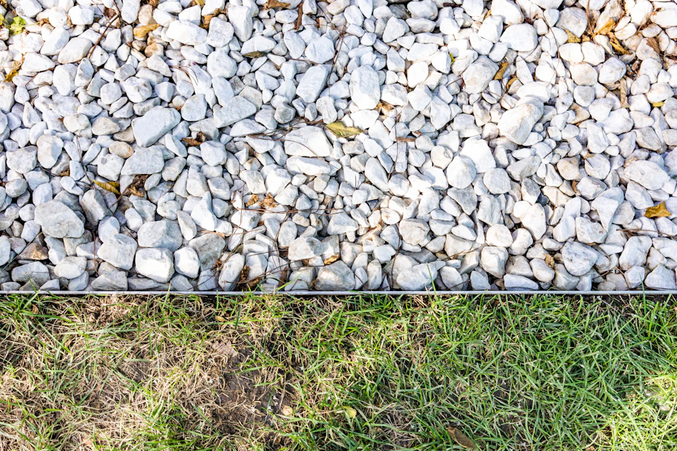 Close-up view of garden path made of white pebbles and rocks with scattered grass
