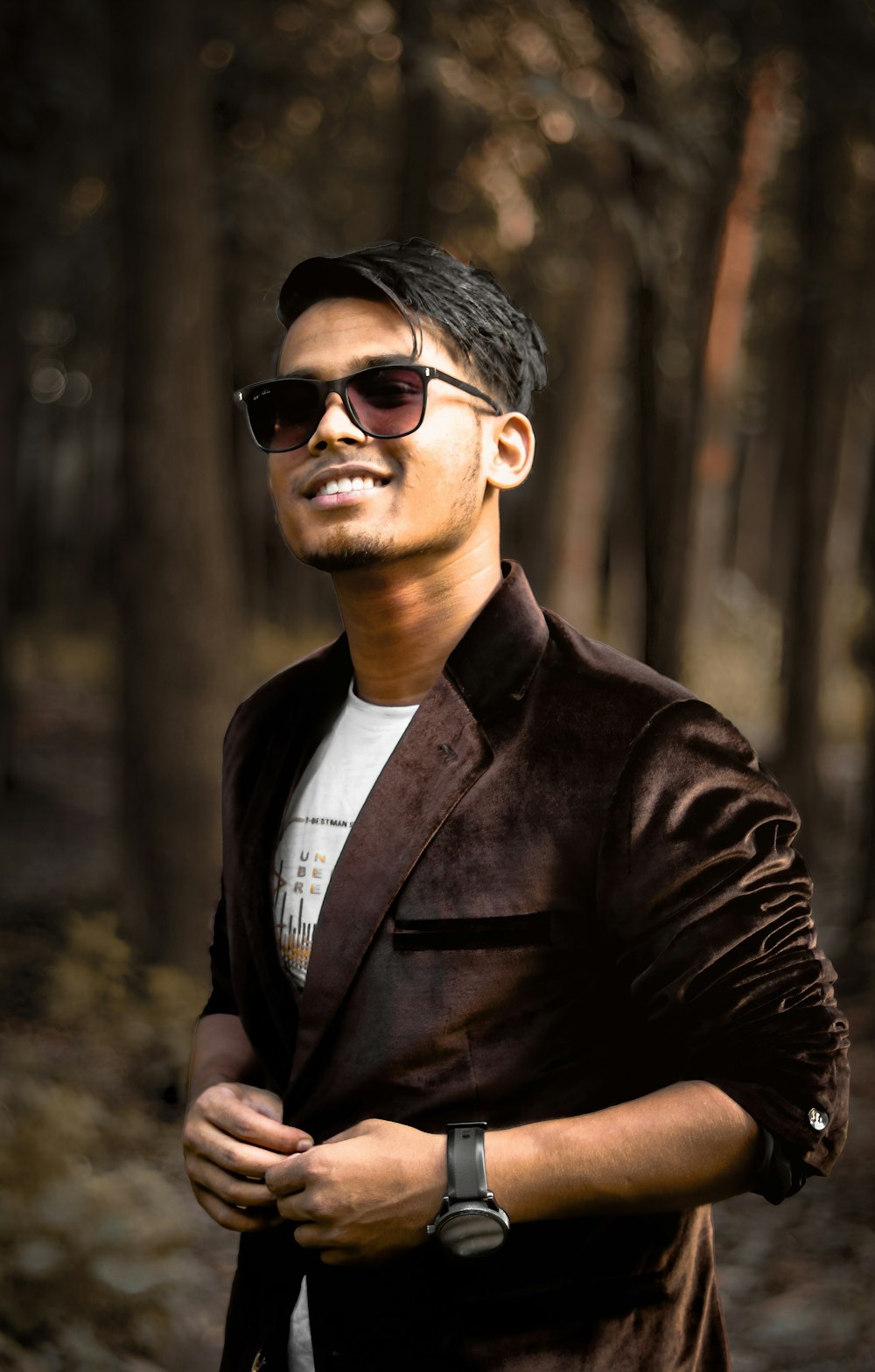 a man in a jacket and sunglasses standing in the woods